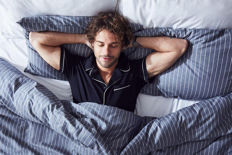 man-sleeping-comfortably-in-navy-striped-bedding 