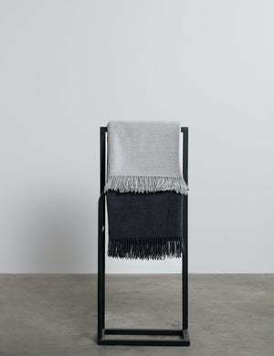 grey and charcoal grey alpaca throws hanging on a rail. 