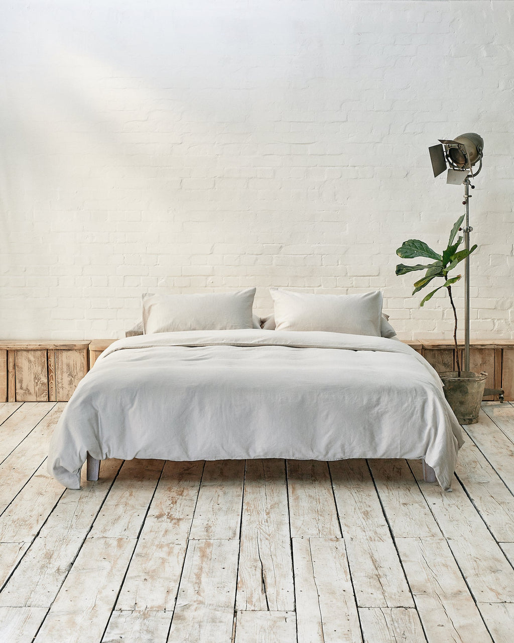 Modern bedroom with light grey bedding and exposed brick wall