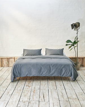 Modern bedroom with navy and white striped bedding and exposed brick wall