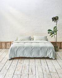 Modern bedroom with light green bedding and exposed brick wall