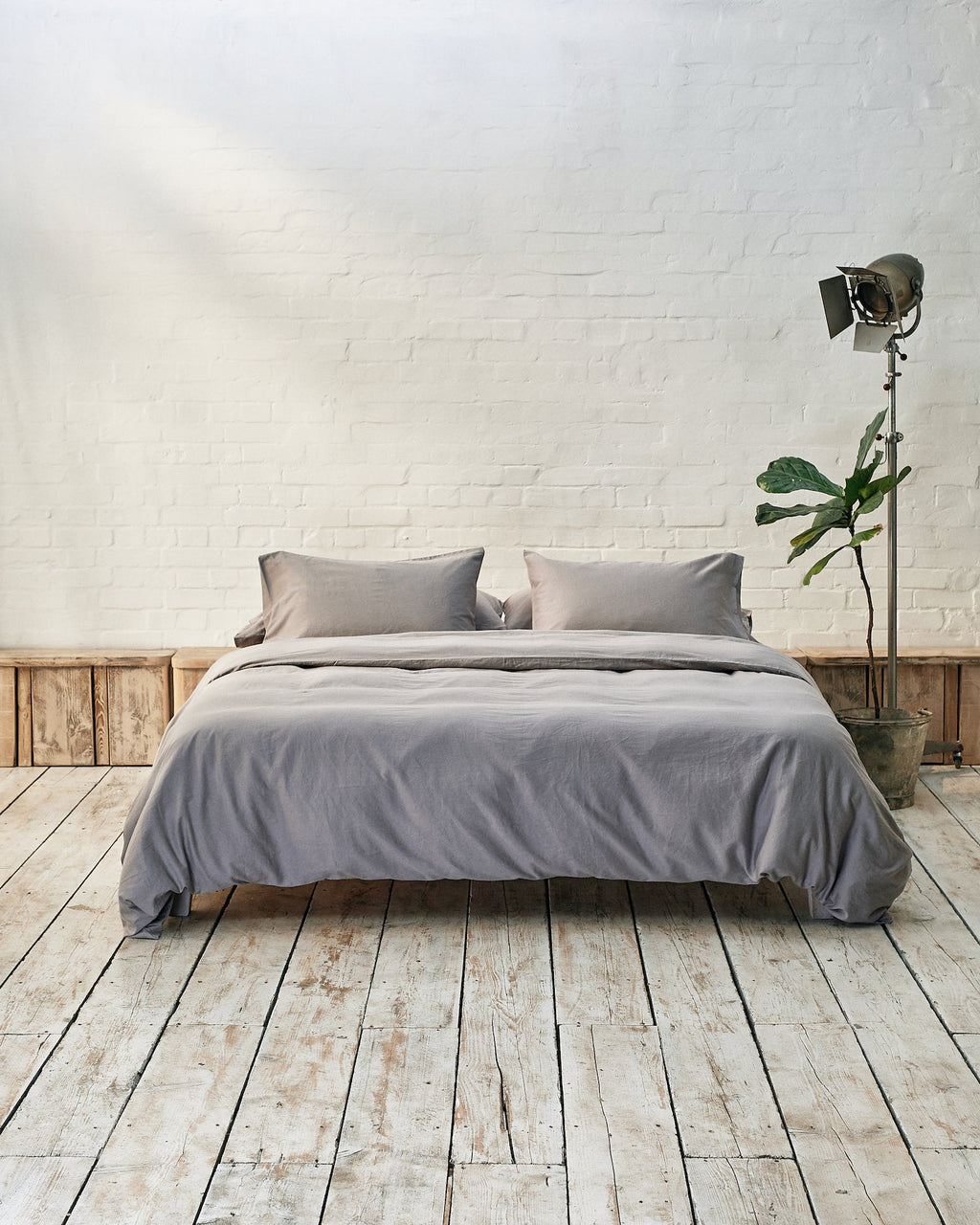 Modern bedroom with silver grey bedding and exposed brick wall